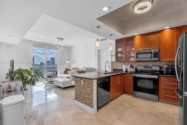 kitchen featuring brown cabinetry, a peninsula, a sink, stainless steel appliances, and tasteful backsplash