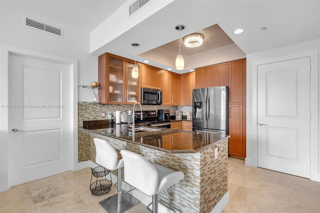 kitchen with sink, a breakfast bar area, hanging light fixtures, dark stone counters, and stainless steel appliances