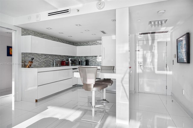 kitchen featuring light tile patterned floors, decorative backsplash, sink, and white cabinets