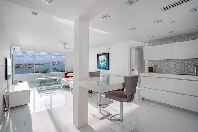 tiled dining space featuring sink, ceiling fan, and a wall of windows