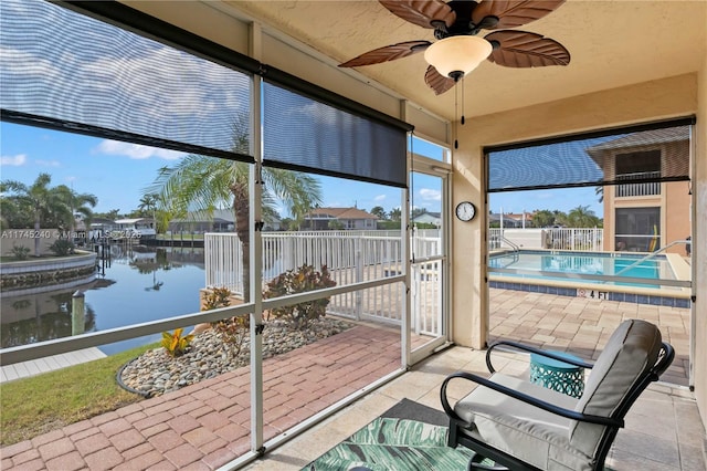 sunroom featuring a water view and ceiling fan