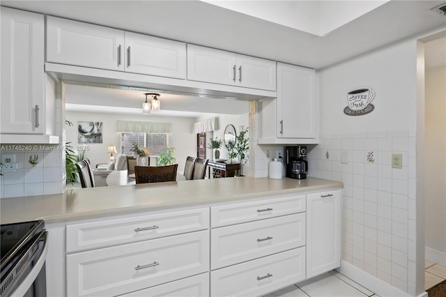 kitchen featuring light tile patterned flooring, electric range oven, tile walls, and white cabinets