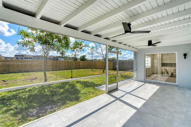 unfurnished sunroom featuring beamed ceiling and ceiling fan