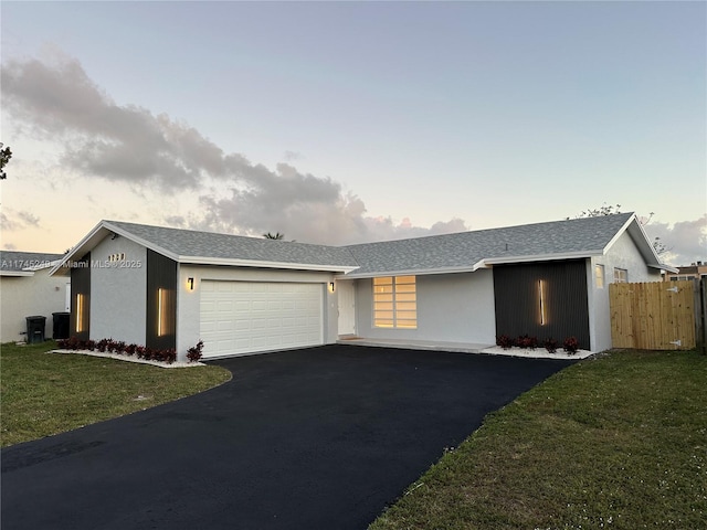 ranch-style house with a garage and a lawn