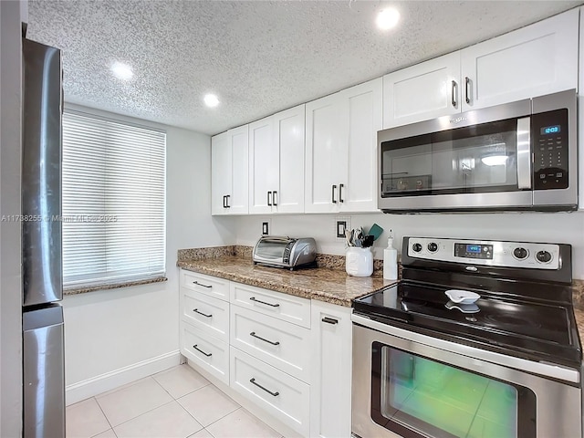 kitchen with light tile patterned flooring, white cabinetry, a textured ceiling, dark stone countertops, and stainless steel appliances