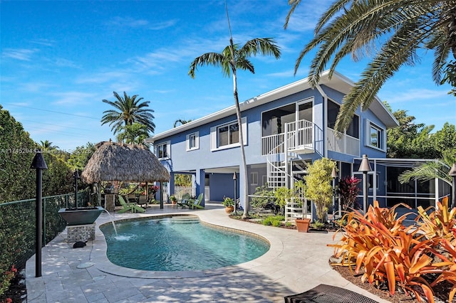 view of pool with a gazebo, pool water feature, a patio, and a sunroom