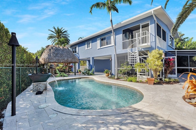 view of swimming pool with a gazebo, a sunroom, pool water feature, and a patio