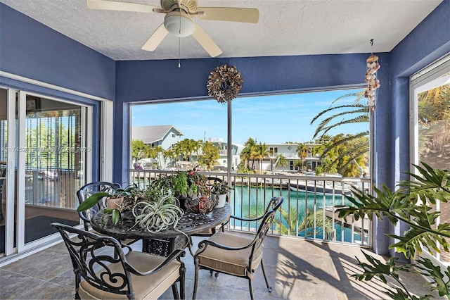 sunroom / solarium with ceiling fan and a water view