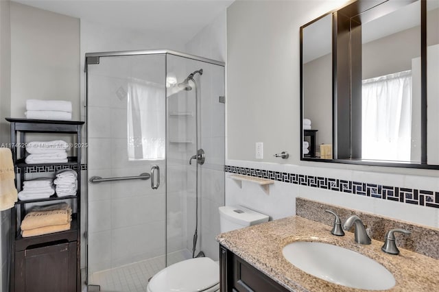 bathroom featuring tasteful backsplash, tile walls, vanity, walk in shower, and toilet