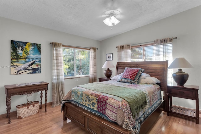 bedroom featuring vaulted ceiling, hardwood / wood-style floors, and a textured ceiling