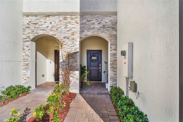 property entrance featuring stucco siding and stone siding