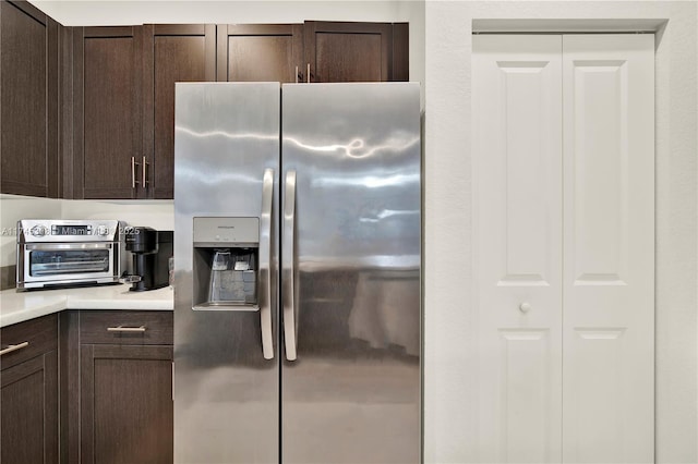 kitchen featuring light countertops, stainless steel fridge, and dark brown cabinetry