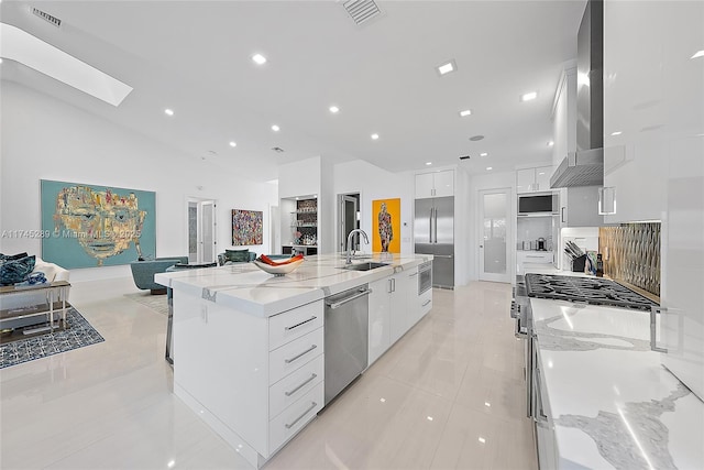 kitchen featuring stainless steel appliances, white cabinetry, sink, and a spacious island