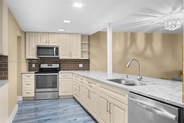 kitchen with appliances with stainless steel finishes, sink, light stone counters, and decorative backsplash