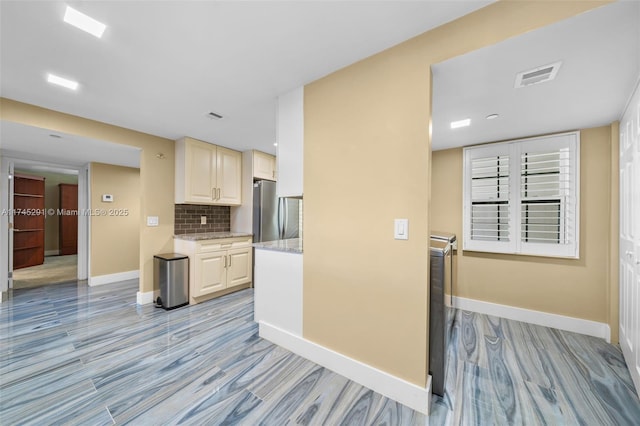 kitchen featuring light stone counters, decorative backsplash, light hardwood / wood-style flooring, and stainless steel refrigerator