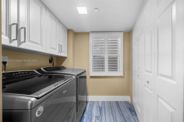 clothes washing area featuring hardwood / wood-style flooring, cabinets, and washer and dryer