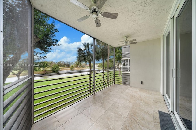 unfurnished sunroom with ceiling fan and a water view