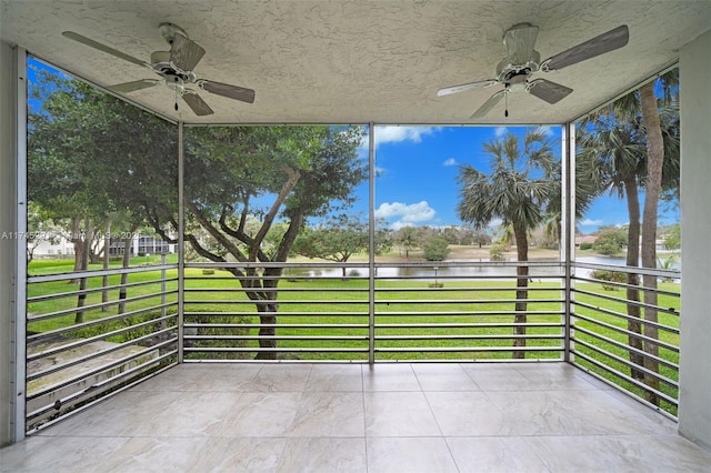 unfurnished sunroom featuring ceiling fan and a water view