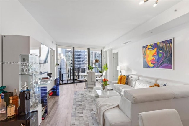 living area with floor to ceiling windows, wood finished floors, and visible vents