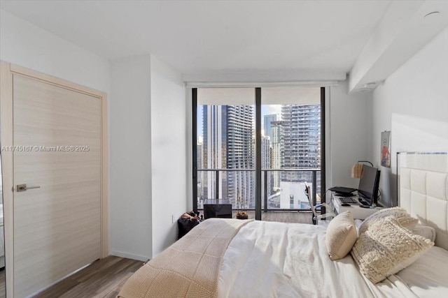 bedroom with expansive windows and wood-type flooring