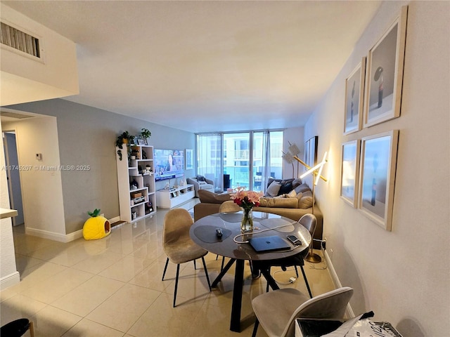 living room with expansive windows, visible vents, baseboards, and light tile patterned flooring