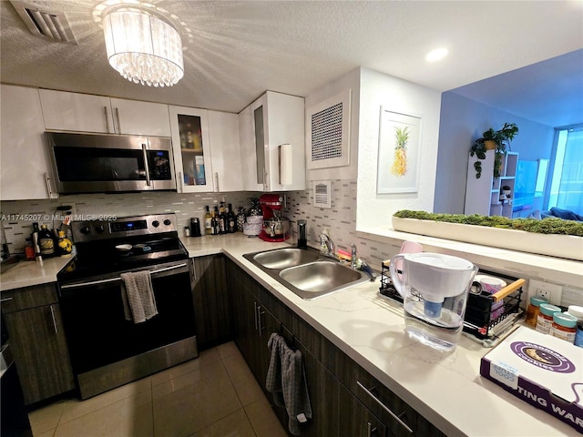 kitchen with white cabinets, glass insert cabinets, stainless steel appliances, light countertops, and a sink