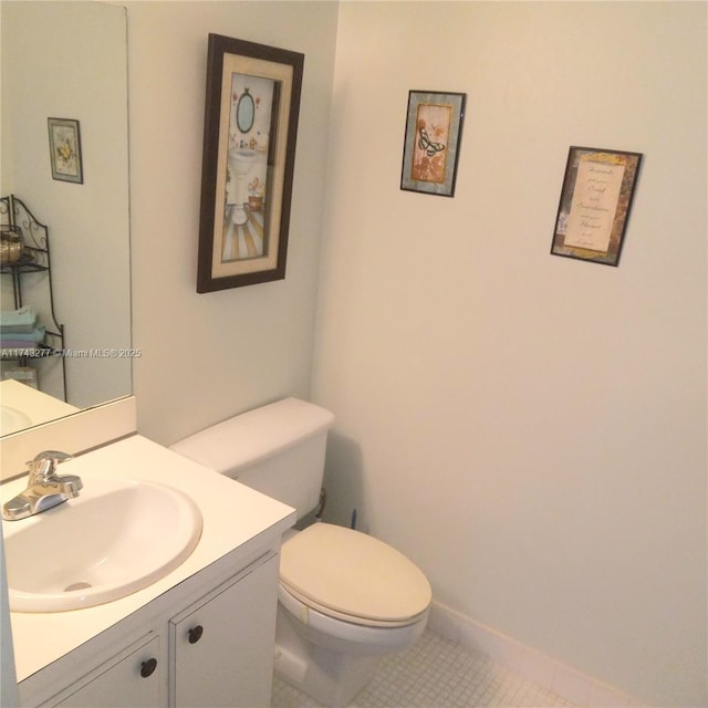 half bathroom featuring toilet, baseboards, vanity, and tile patterned floors