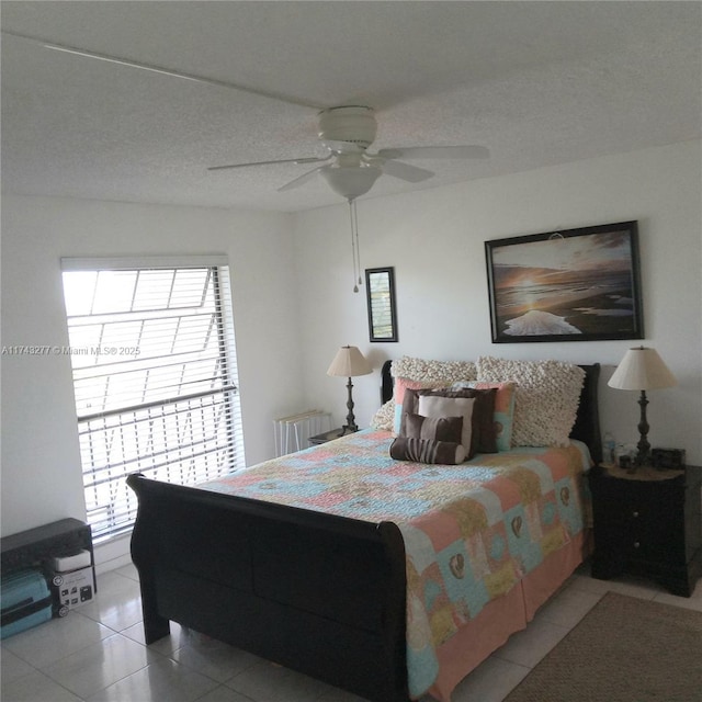 bedroom featuring a ceiling fan, light tile patterned flooring, and radiator heating unit