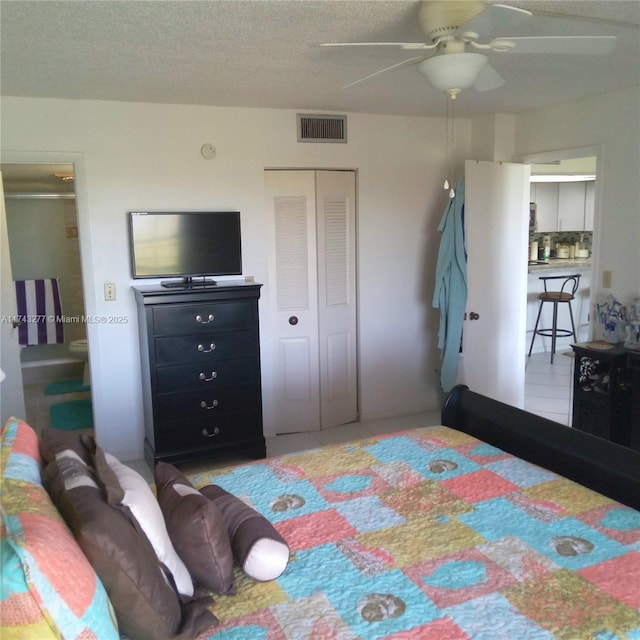 bedroom featuring a closet, visible vents, a textured ceiling, and tile patterned floors