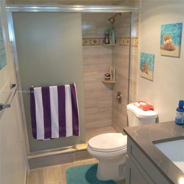 bathroom with a stall shower, vanity, and toilet