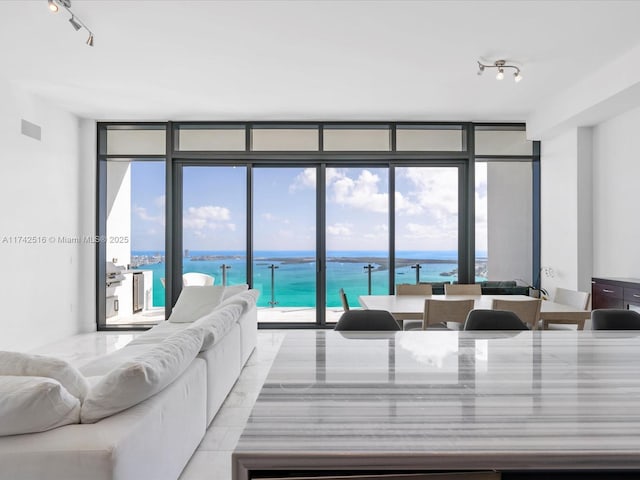 living room featuring a water view, floor to ceiling windows, and rail lighting