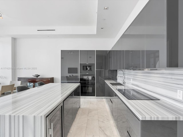 kitchen with sink, gray cabinets, black appliances, and a center island