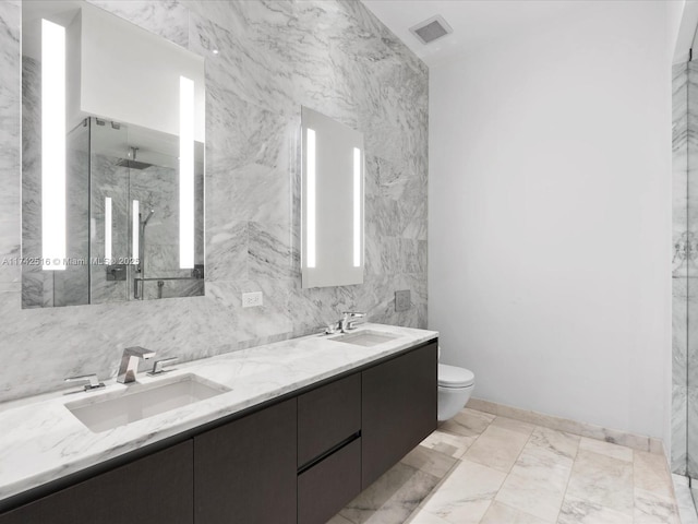 bathroom with vanity, toilet, a shower with shower door, and tile walls