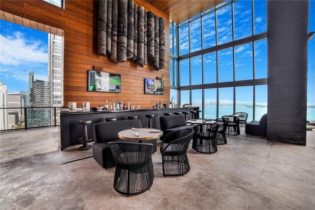 1451 Brickell Ave Unit 5101, Miami, FL 33131 - living area featuring a high ceiling, wood walls, healthy amount of natural light, concrete flooring, and a community bar