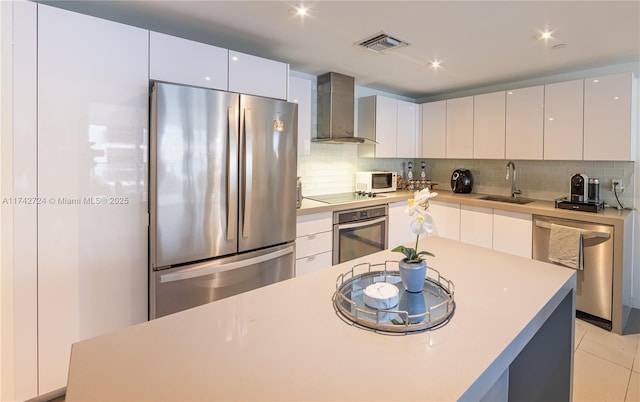 kitchen with appliances with stainless steel finishes, wall chimney range hood, and white cabinets