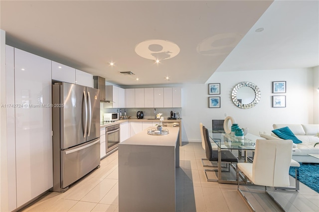 kitchen with white cabinetry, an island with sink, wall chimney exhaust hood, and appliances with stainless steel finishes