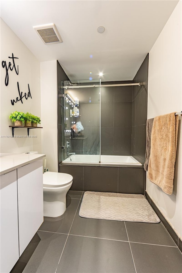 full bathroom with tile patterned flooring, vanity, combined bath / shower with glass door, and toilet