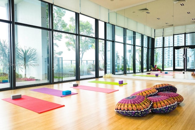 exercise area with a high ceiling, floor to ceiling windows, and wood-type flooring