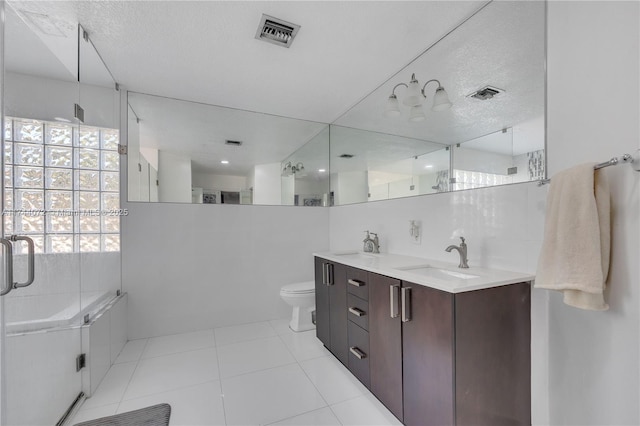 bathroom with tile patterned flooring, vanity, a textured ceiling, toilet, and walk in shower