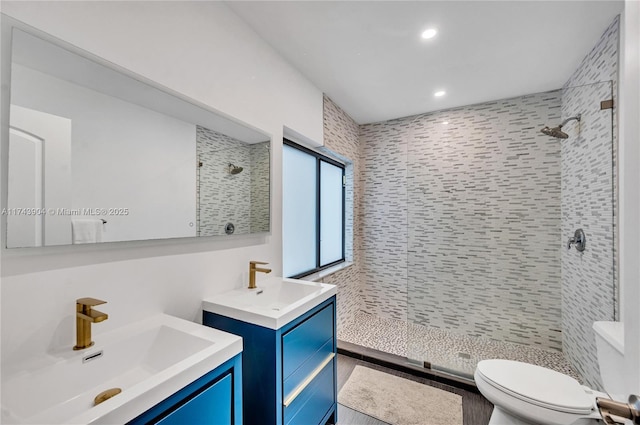 bathroom featuring vanity, toilet, and a tile shower