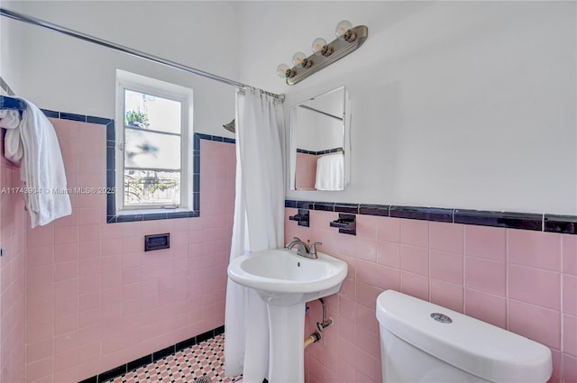 bathroom with toilet, a shower with shower curtain, and tile walls