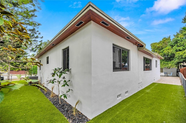 view of side of property with a patio area, a lawn, and central air condition unit