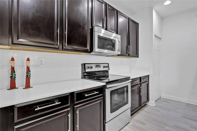 kitchen with light wood-style flooring, light countertops, baseboards, and appliances with stainless steel finishes
