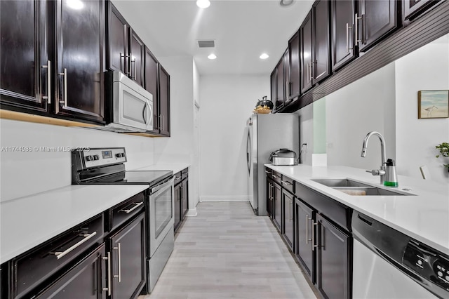 kitchen with appliances with stainless steel finishes, sink, and light hardwood / wood-style flooring