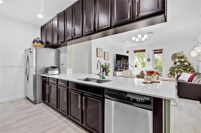 kitchen with a sink, open floor plan, light countertops, appliances with stainless steel finishes, and light wood-style flooring