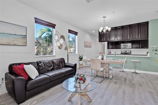 living room featuring recessed lighting, a notable chandelier, light wood-type flooring, and baseboards