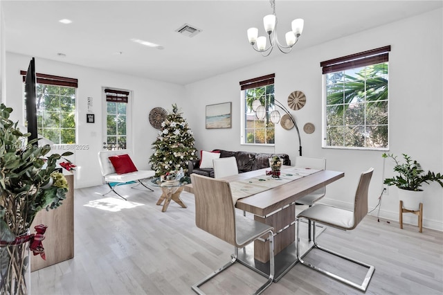 dining area with an inviting chandelier, plenty of natural light, and light hardwood / wood-style flooring