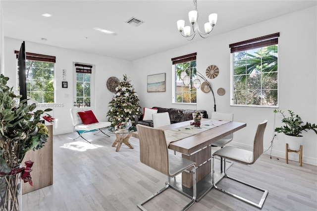 dining space featuring an inviting chandelier, light wood-style floors, baseboards, and visible vents