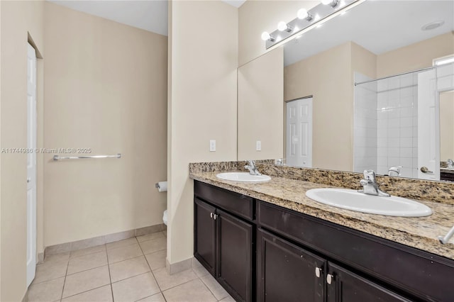 bathroom with toilet, tile patterned floors, double vanity, and a sink