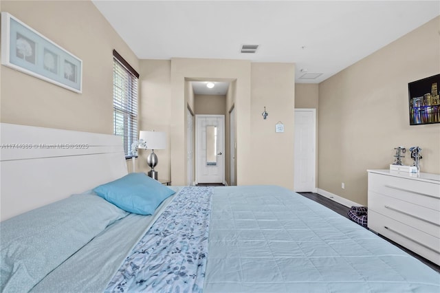 bedroom with visible vents, baseboards, and wood finished floors